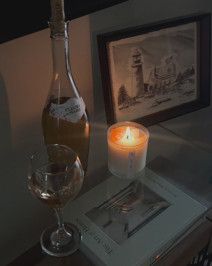 A lit crystal candle sitting next to a glass of wine